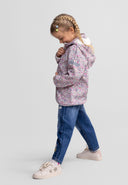 Young girl wearing a floral print wind resistant jacket with hood, paired with casual jeans and sneakers.