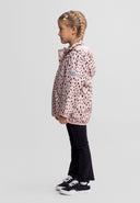 Young girl wearing a pink softshell jacket with a unique black dot design and hood, styled with black pants and sneakers