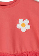 Close-up of a girls' orange jersey dress with a white flower embroidery on the bodice.