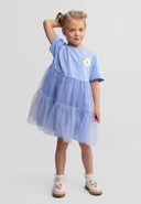 Young girl wearing a blue layered tulle dress with a flower detail, posing confidently in kids fashion style.