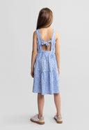 Young girl wearing a blue floral sleeveless tiered dress with adjustable back bow design in kids fashion style