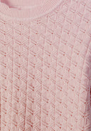 Close-up of pink knit jumper with intricate geometric wave-shaped pattern and crew neck design for kids fashion.