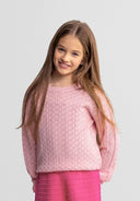 Smiling young girl wearing a pink textured jumper with a wave-shaped hem and crew neck design in kids fashion.