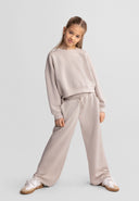 Young girl modeling beige wide leg joggers with adjustable waist and side pockets, showcasing a stylish kids fashion design.