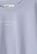 Close-up of blue viscose sweatshirt with embroidered white text design and round neckline by Minoti.