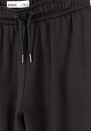 Close-up of black joggers elasticated waist with drawstring detail and smooth viscose blend fabric design