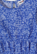 Close-up of blue floral textured fabric with white flowers and gathered waist detail on girls top design.