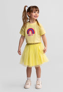Smiling girl wearing a light yellow tulle skirt and matching summer-themed top, showcasing kids fashion design.