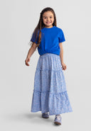 Young girl wearing a blue floral maxi skirt with an elasticated waistband and casual blue top, smiling confidently