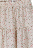 Close-up of cream maxi skirt with elastic waistband and delicate small floral print design for girls.