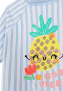 Blue and white striped kids rash vest with a playful pineapple design and cheerful floral accents for sun protection.