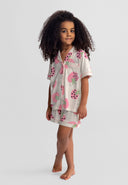 young girl wearing cream and pink short sleeve pajama set with strawberry design standing barefoot