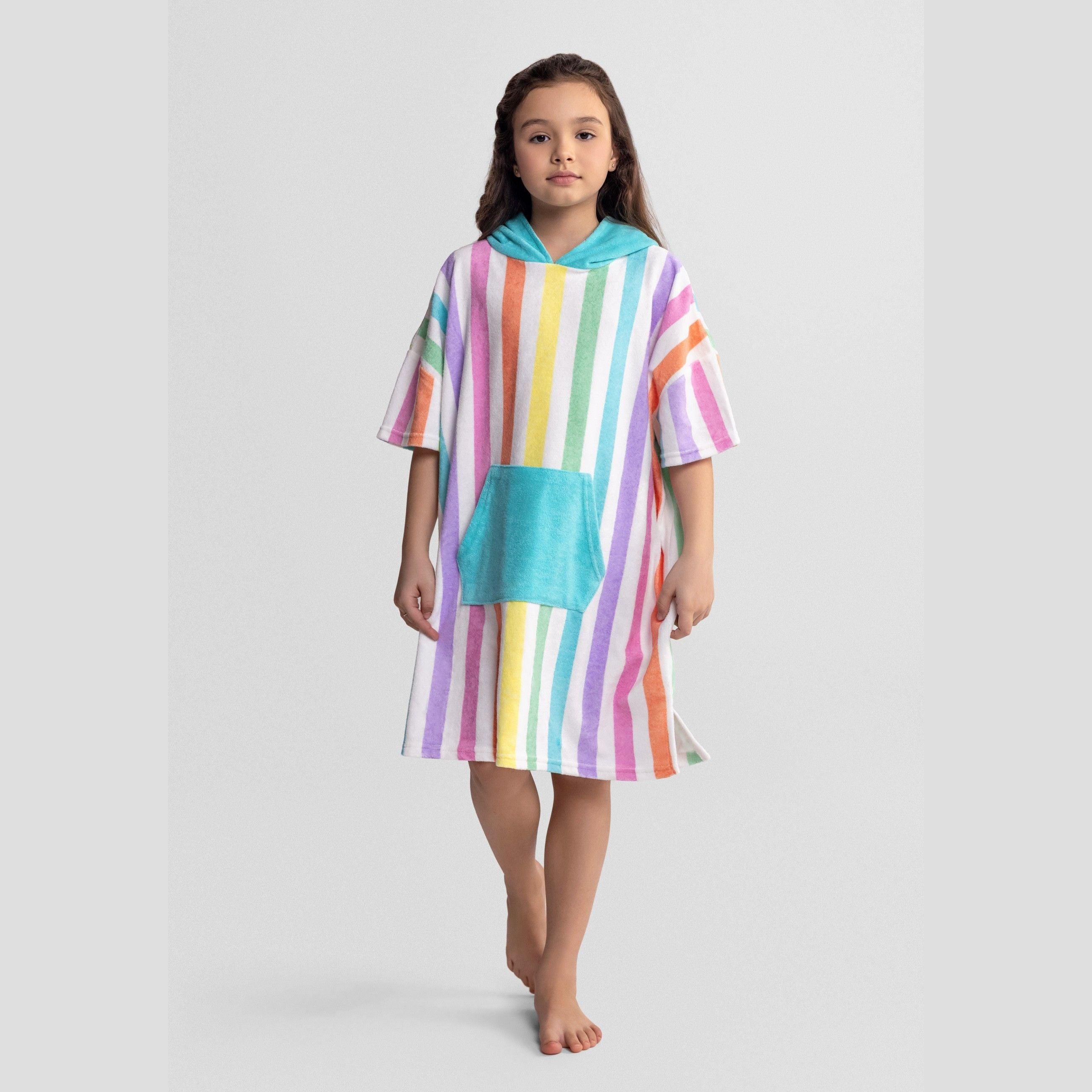 Young girl wearing rainbow striped hooded towelling cover-up, knee-length with turquoise hood and pocket, standing against white background