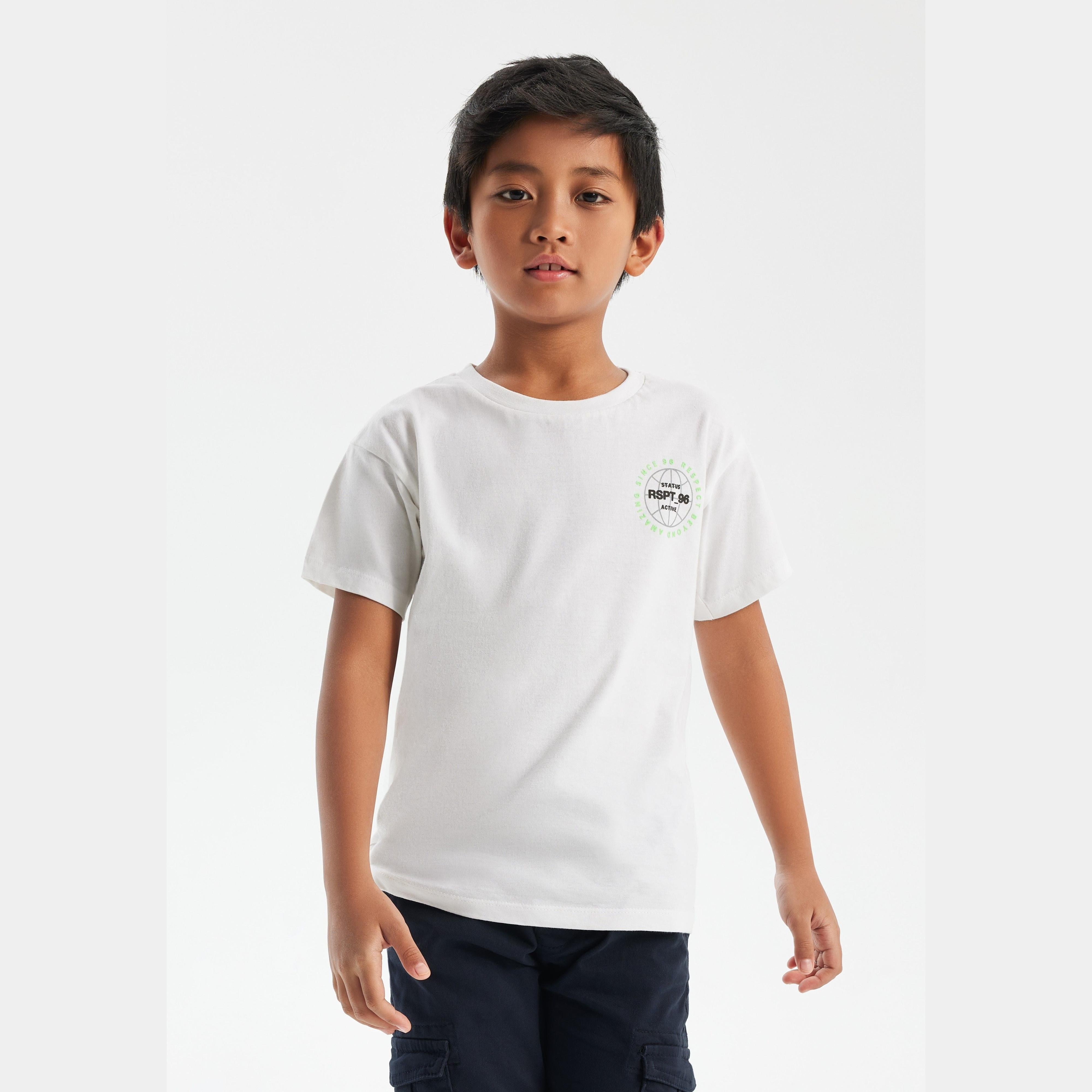 Young boy wearing white t-shirt with small chest logo, paired with navy cargo pants, standing against light grey background