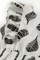 Girls summer printed dress with frills white 1-8y featuring bold black leaf print and soft flowing fabric. Enhance your child's summer wardrobe.