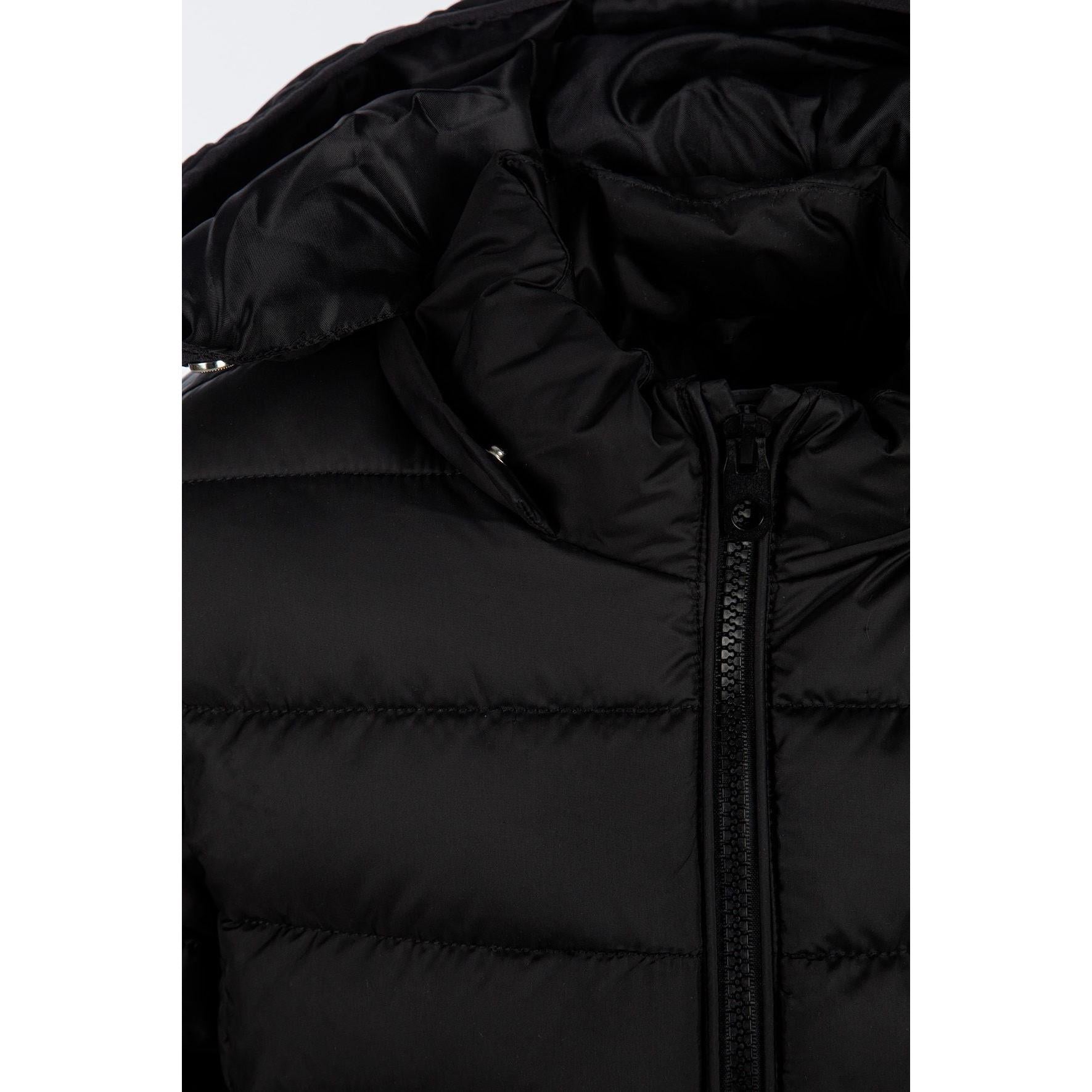 Detail view of black quilted jacket sleeve showing padded construction and embossed circular Minoti logo patch