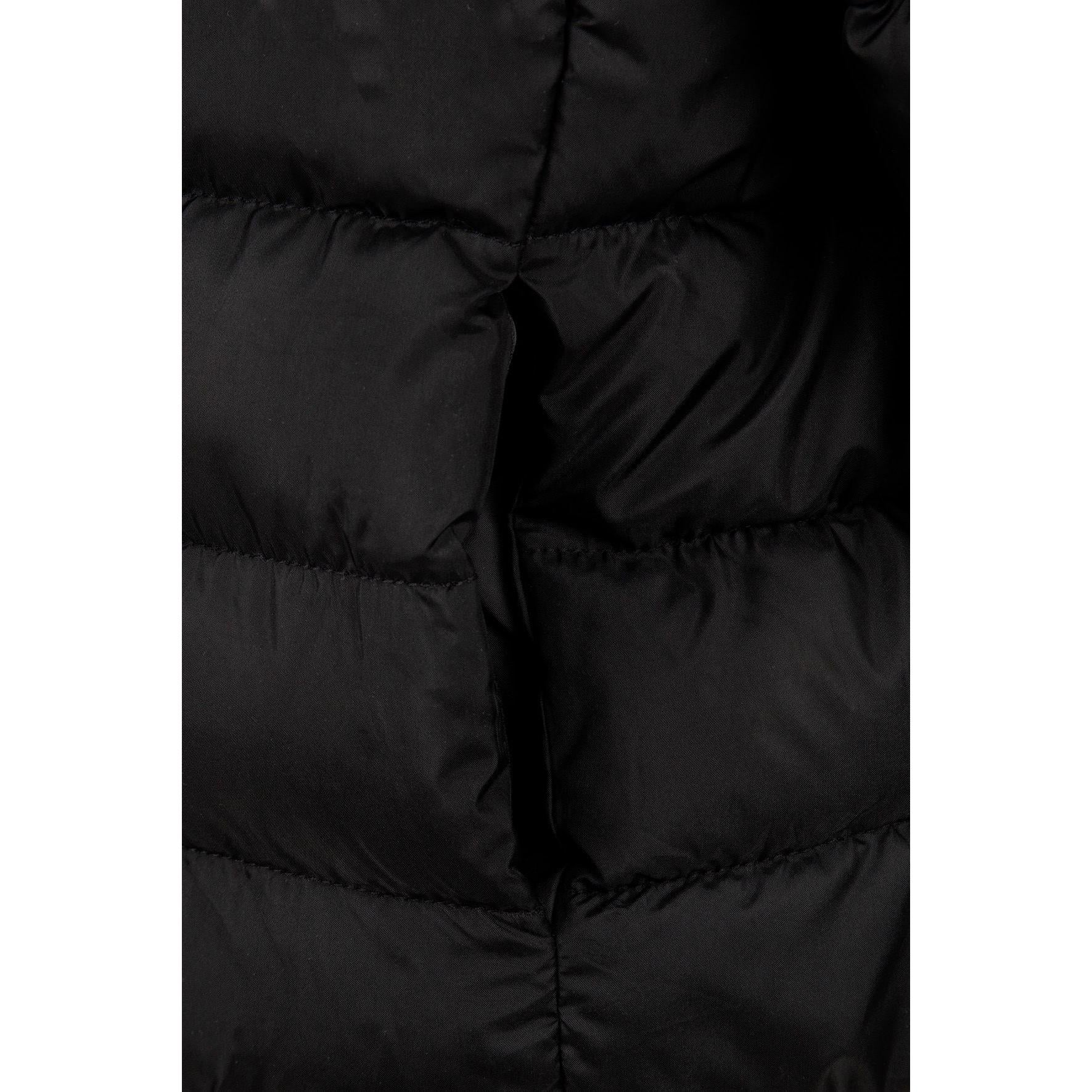 Detail view of black quilted jacket sleeve showing padded construction and embossed circular Minoti logo patch