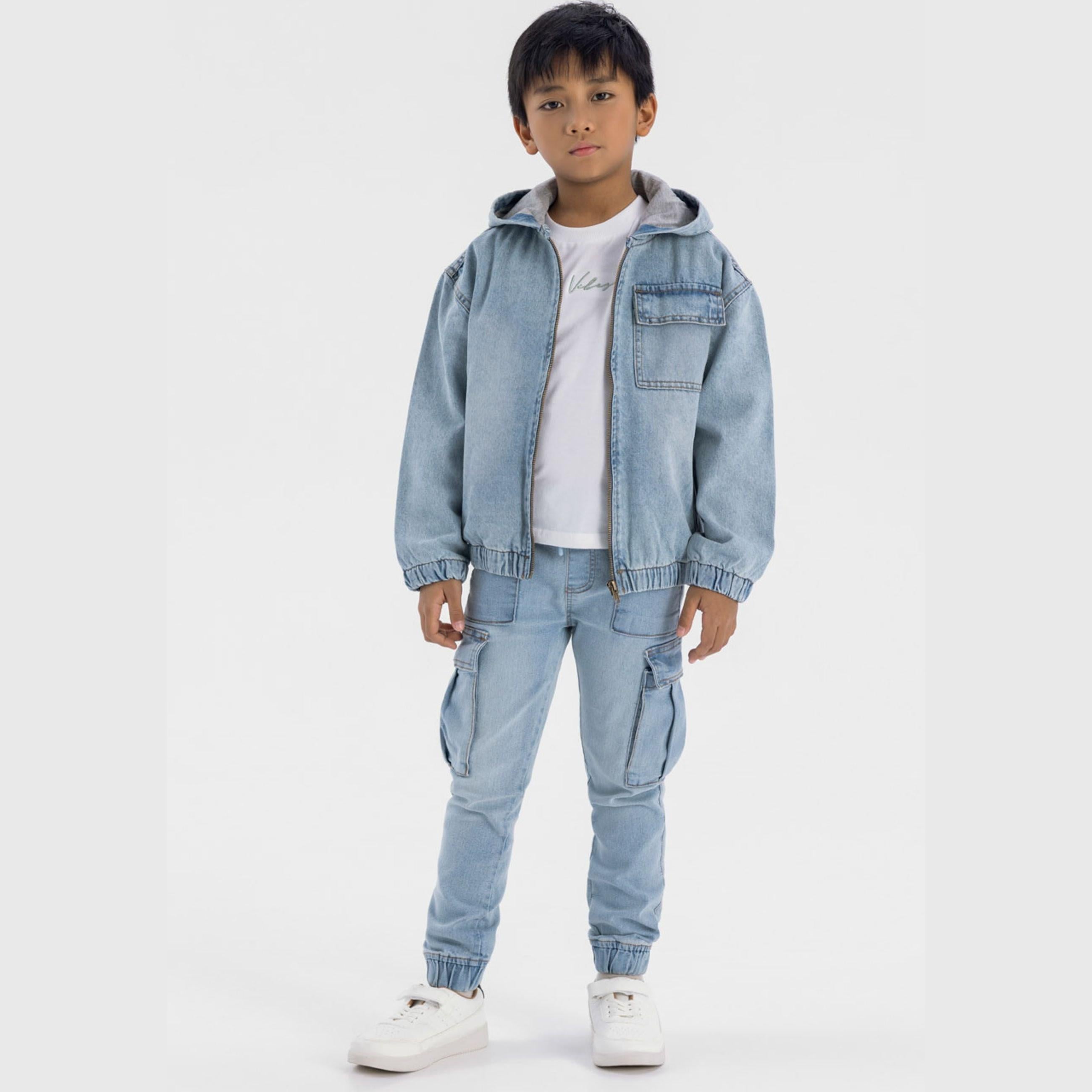 Boy wearing light blue hooded denim jacket with white t-shirt and matching cargo pants, standing against white background