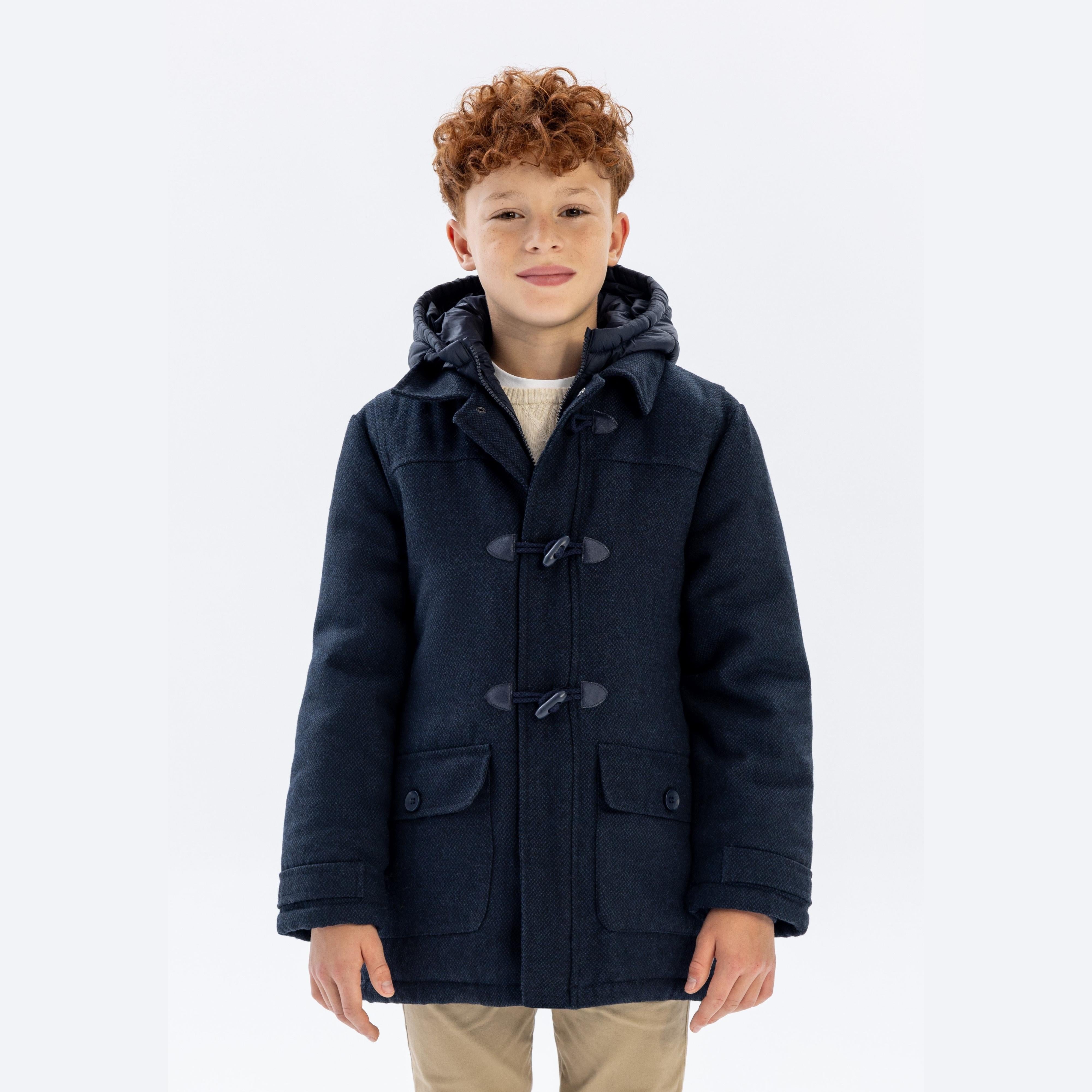 Boy wearing navy duffle coat with nylon hood, front view on white background showing toggle fastenings and patch pockets
