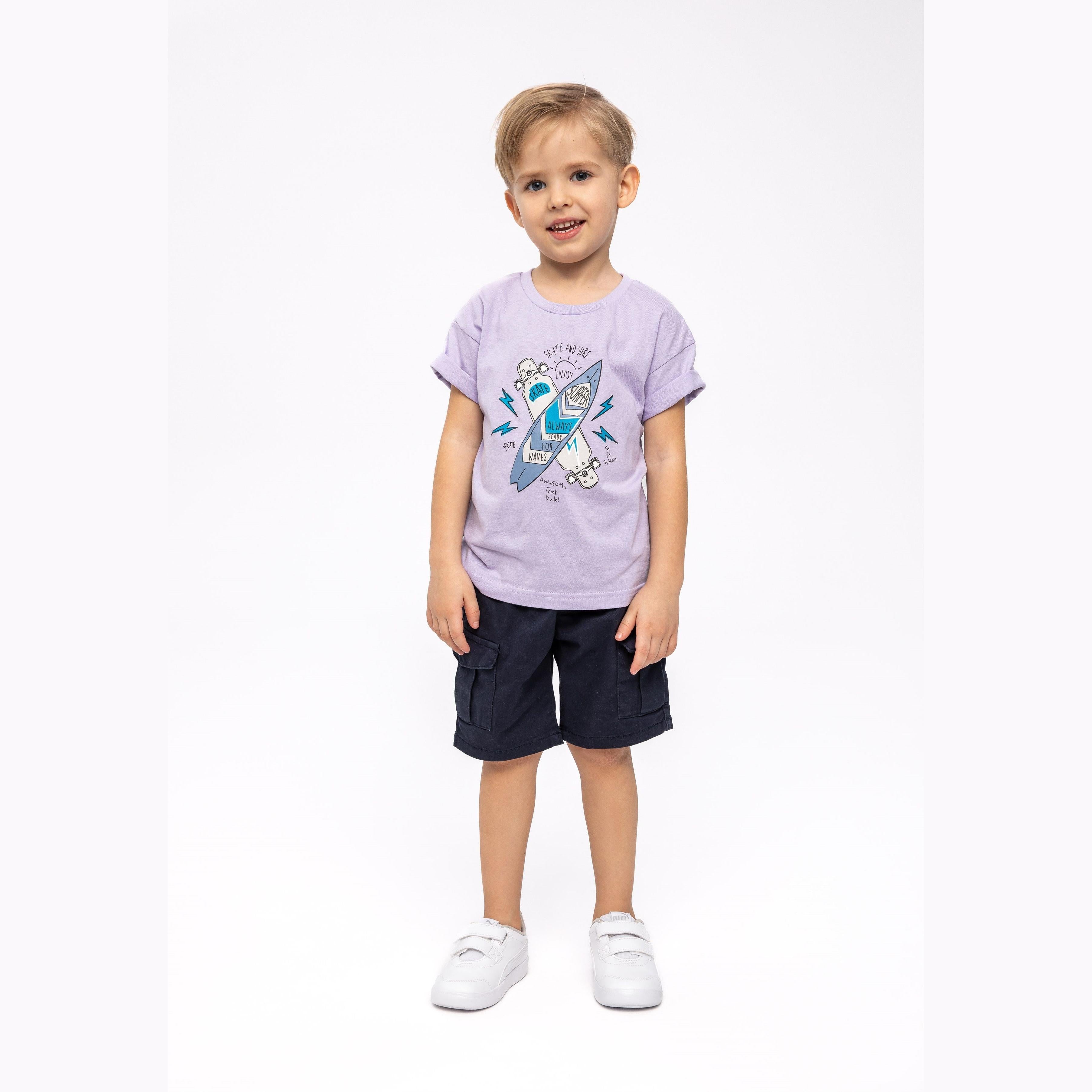 Young child wearing purple t-shirt with skateboard graphic and navy shorts, standing against white background