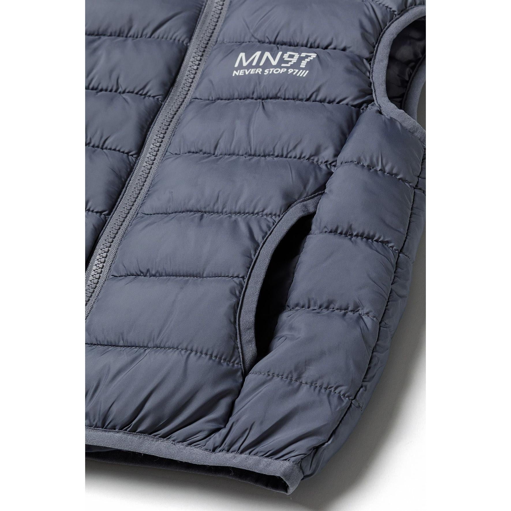 Close-up detail of grey padded gilet showing MN97 chest print, Minoti internal label and quilted texture