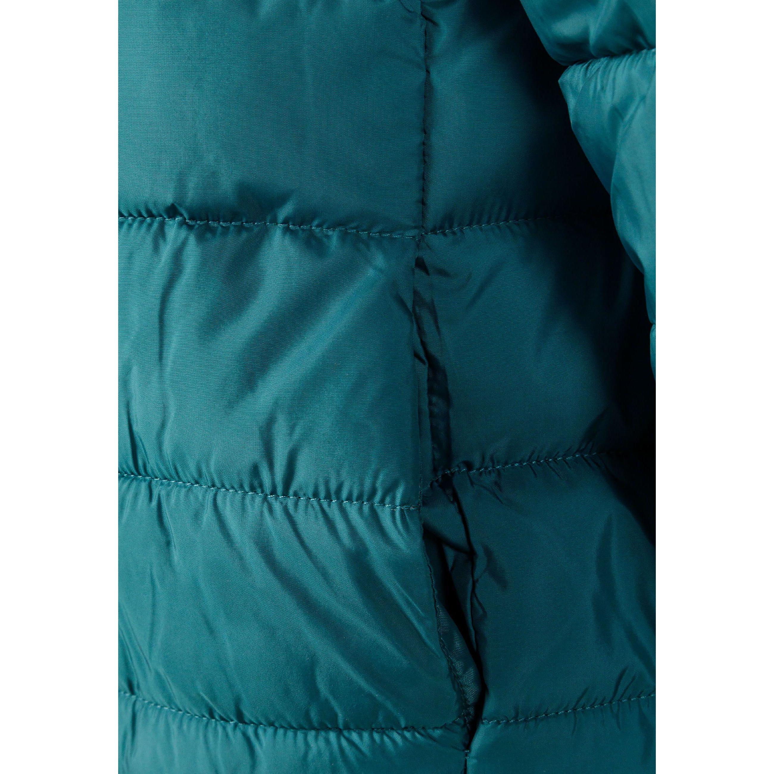 Close-up detail of turquoise padded jacket showing circular black logo patch with cross design and compass directions