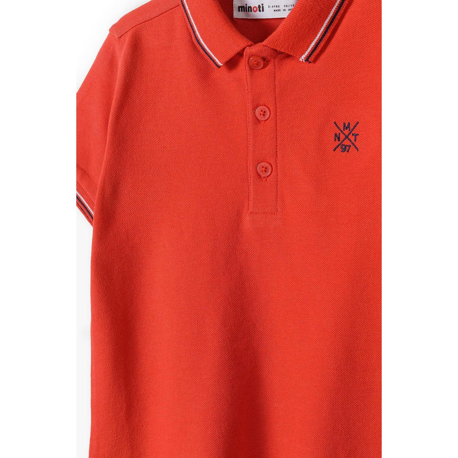 Close-up detail of red polo shirt showing button placket, embroidered logo and contrast tipping on collar
