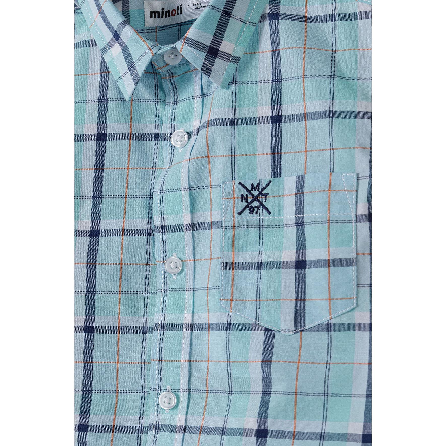 Close-up detail of light blue checked shirt showing Minoti brand label, collar construction, button placket and chest pocket with embroidered logo