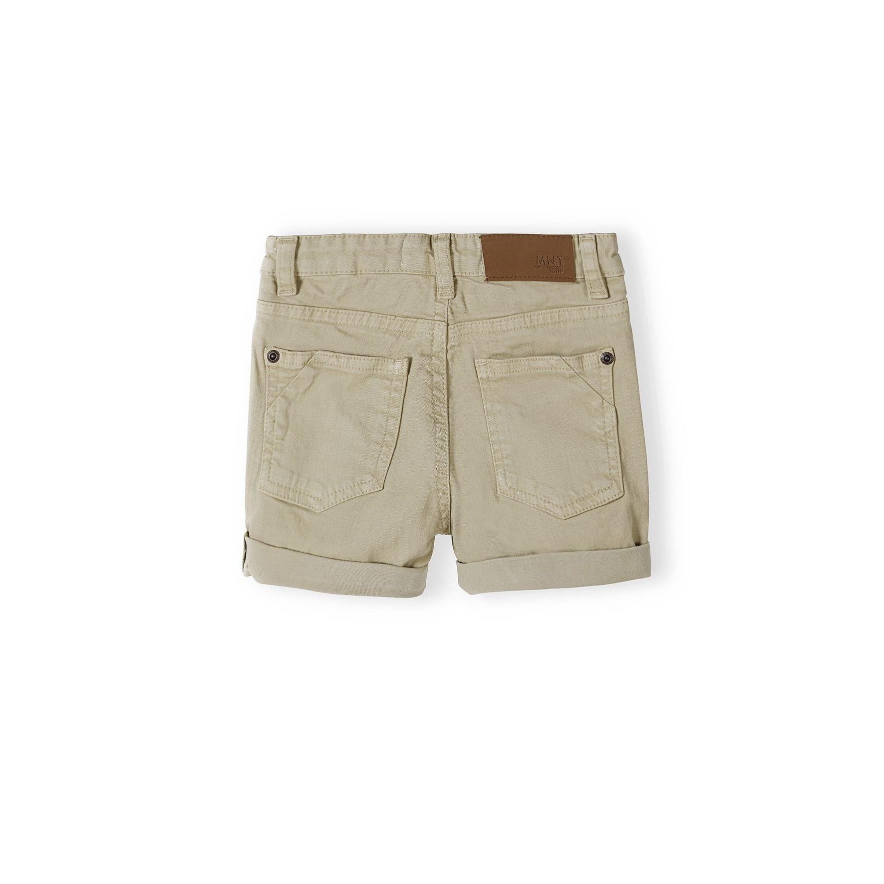 Back view of beige twill shorts showing five pocket design with brown leather waistband label on white background