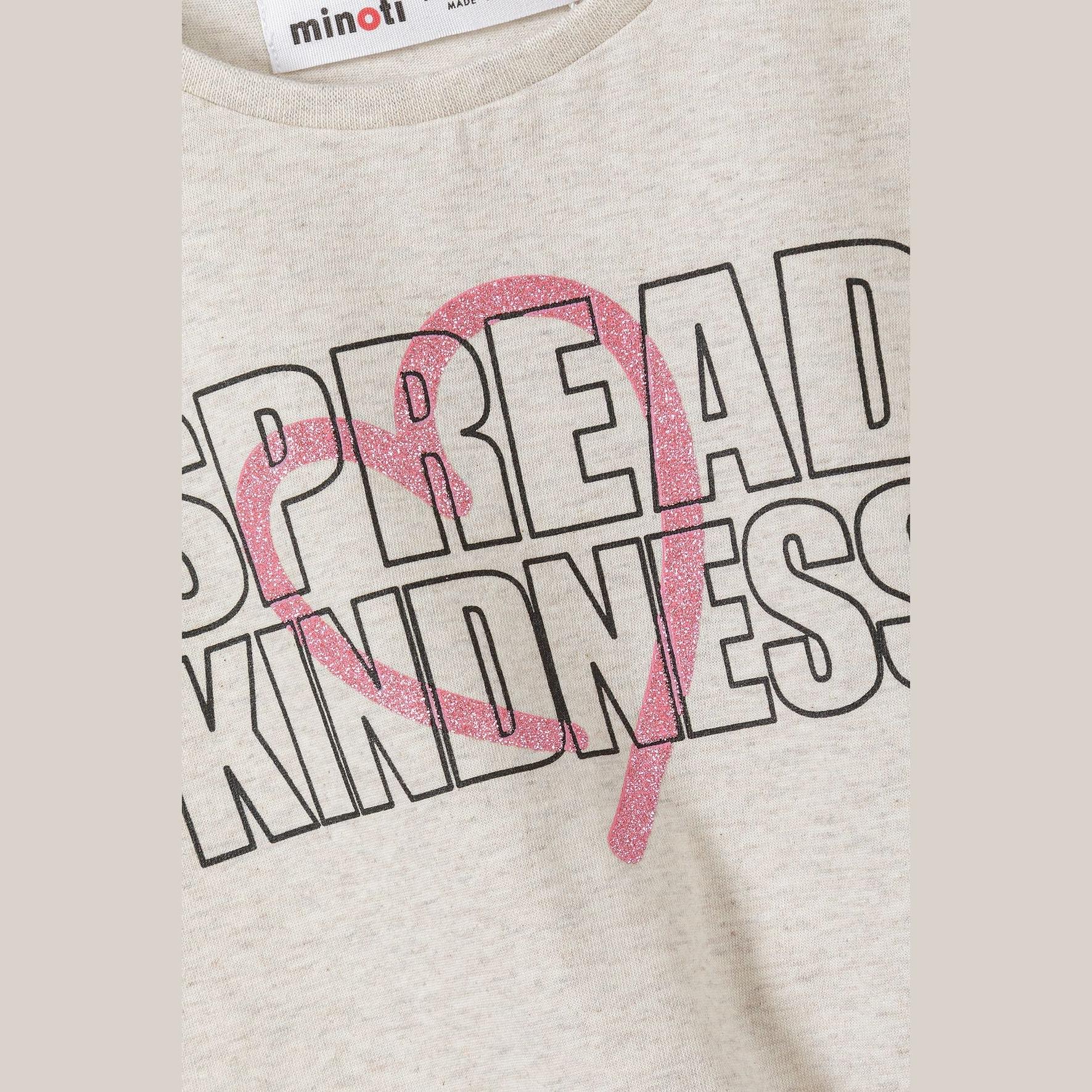 Close-up detail of Spread Kindness text in outlined letters with pink glittery heart overlay on beige fabric, showing Minoti label
