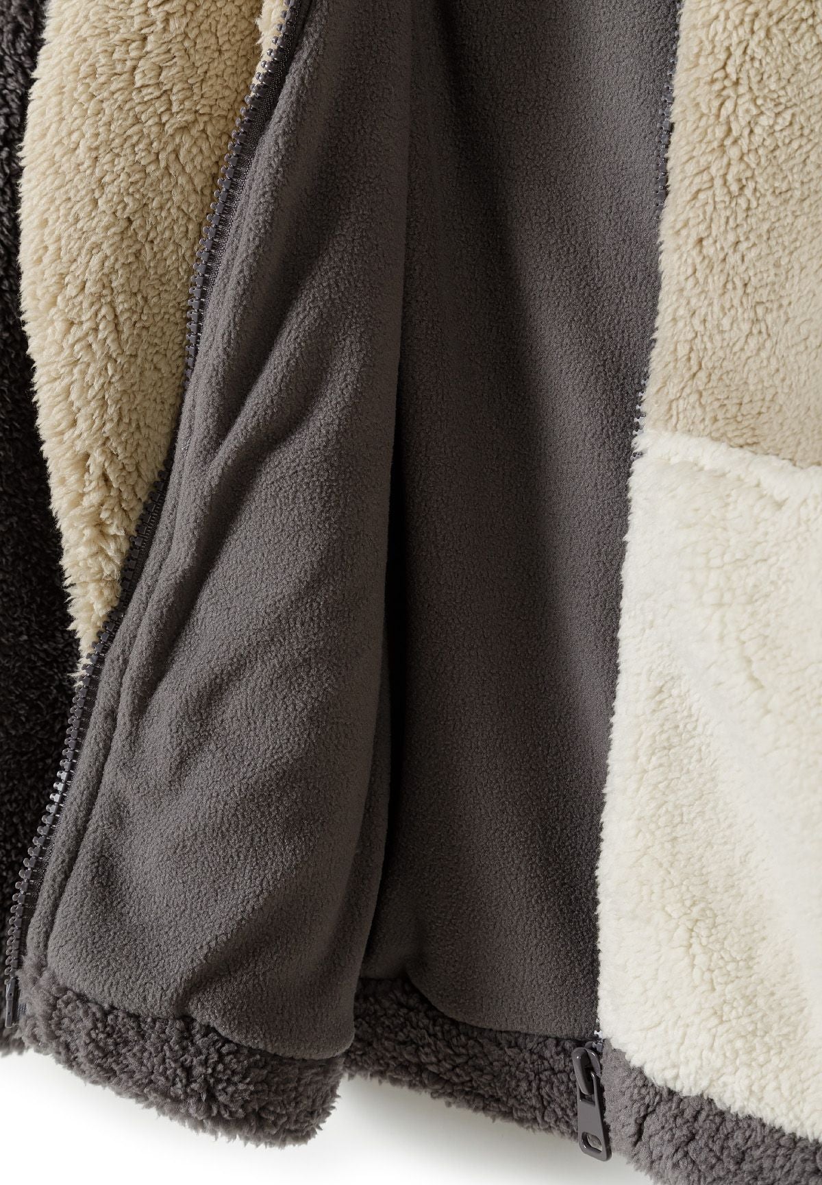 Close-up detail of sherpa fleece jacket showing zip fastening, soft lining and colourblock fabric construction