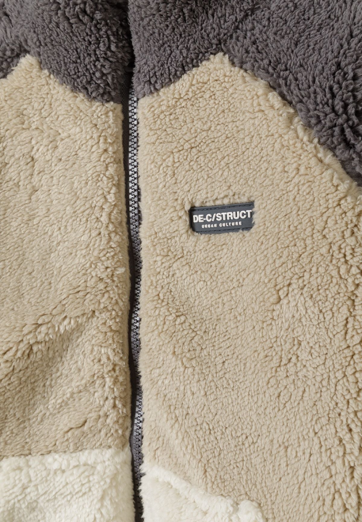 Close-up detail of sherpa fleece jacket showing zip fastening, soft lining and colourblock fabric construction
